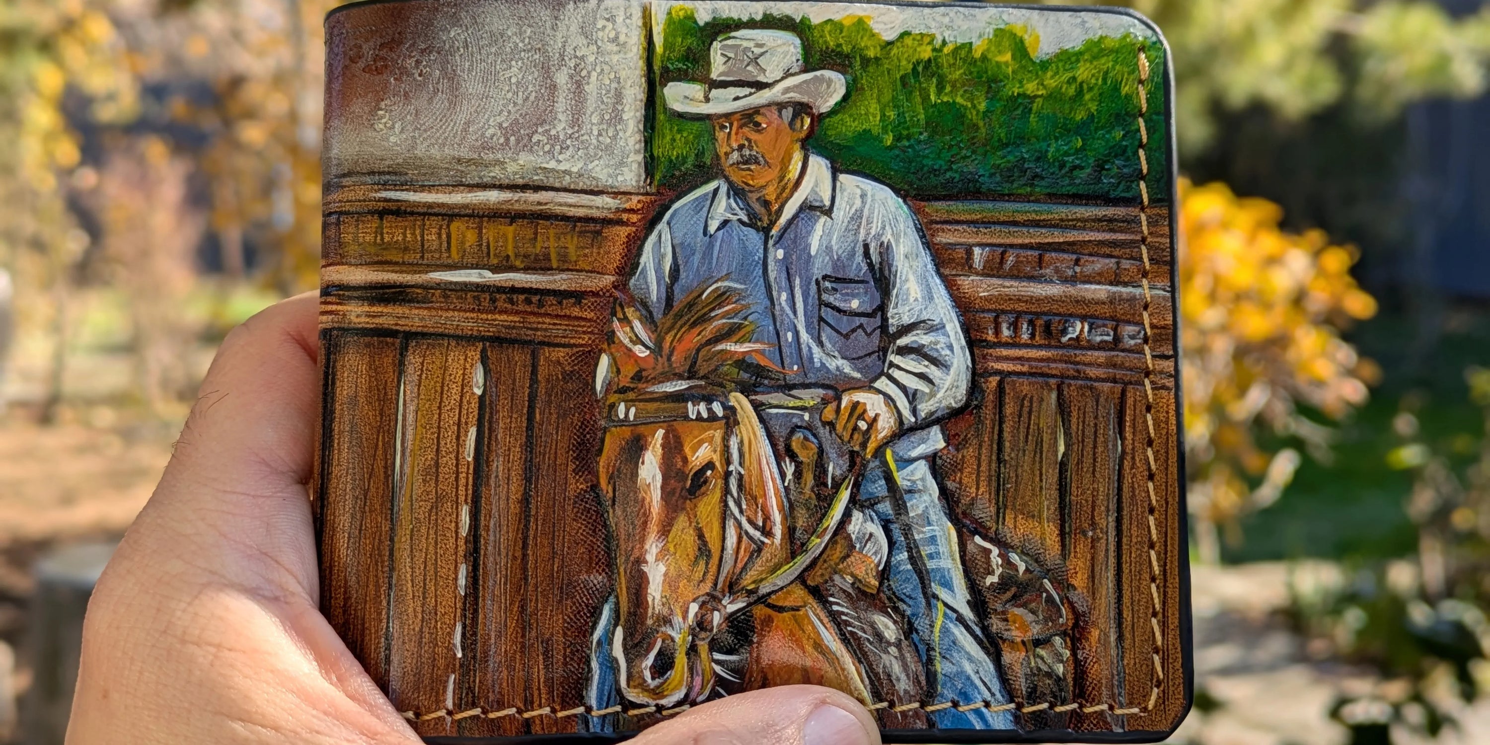 Custom hand-tooled leather bifold wallet featuring a painted portrait of a cowboy riding a horse, unique gift for dad.