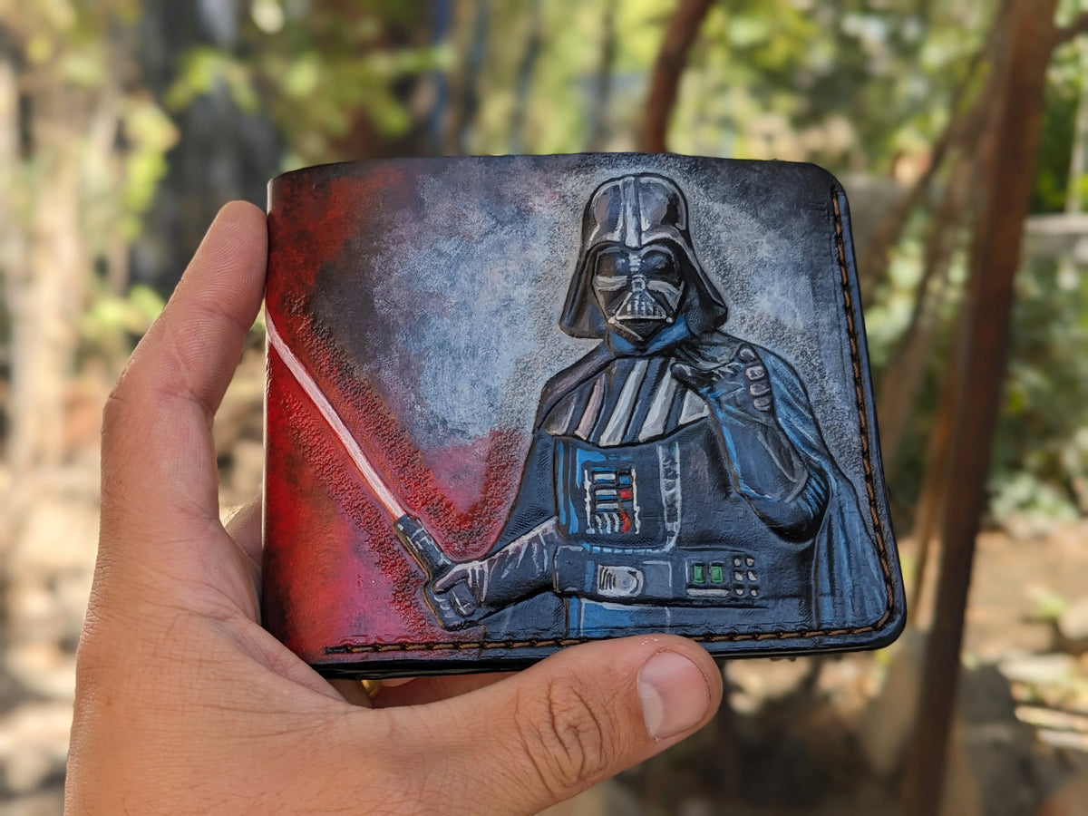 Close-up of a hand holding a long, hand-carved Star Wars leather biker wallet featuring a detailed Darth Vader design.