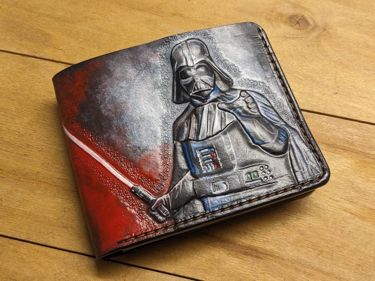 Hand-tooled leather bifold wallet featuring a carved, hand-painted Darth Vader holding an ignited red lightsaber.