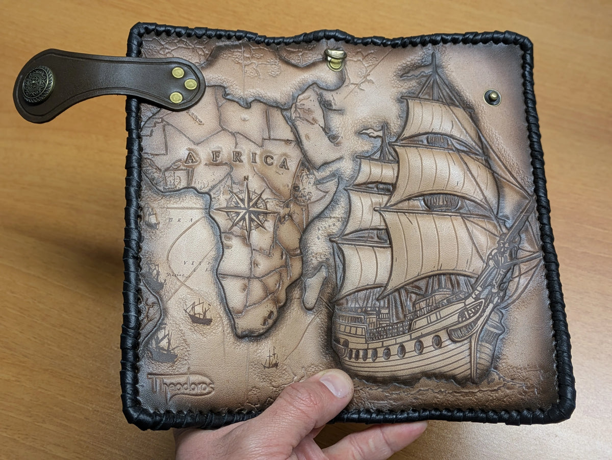 Full view of open leather travel wallet showcasing the combined hand-tooled maritime scene with Africa map and sailing ship.