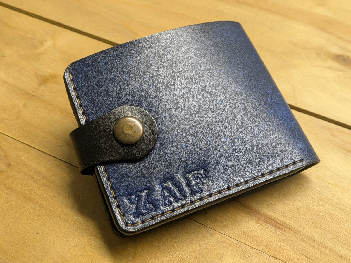 Back view of custom leather wallet with "ZAF" initials embossed, showing hand-stitching and snap button detail.