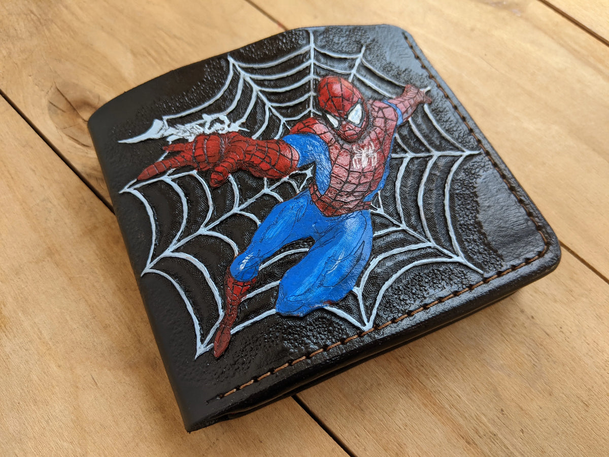 Close-up view of a handmade leather bifold wallet with an embossed and painted Marvel Spider-Man, showing detailed stitching.