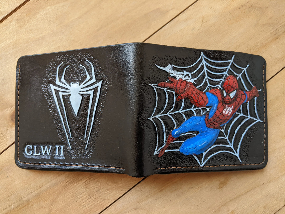 Opened custom full-grain leather bifold wallet by Theodoros, showcasing a hand-carved Spider-Man design and a spider logo.
