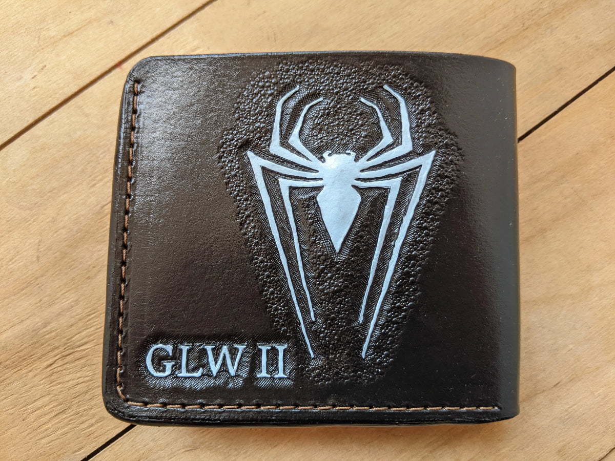 Back cover view of a custom leather wallet featuring a hand-tooled spider logo and custom engraved initials by Theodoros leather.