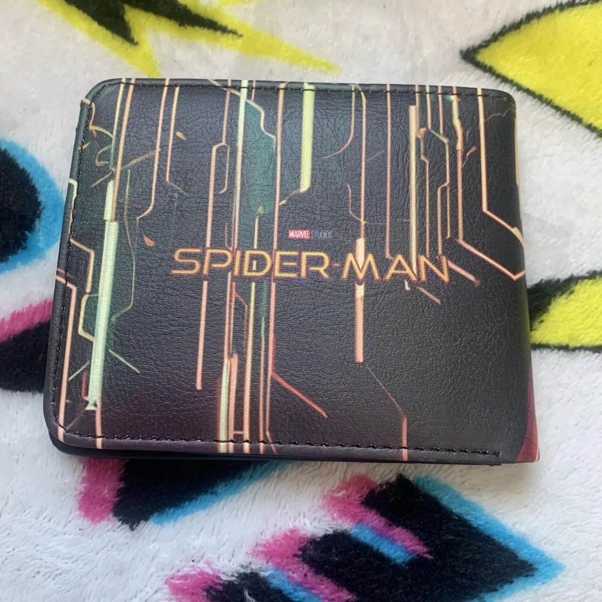 Back view of a black full-grain leather bifold wallet featuring Marvel Studios Spiderman text logo with circuit designs.