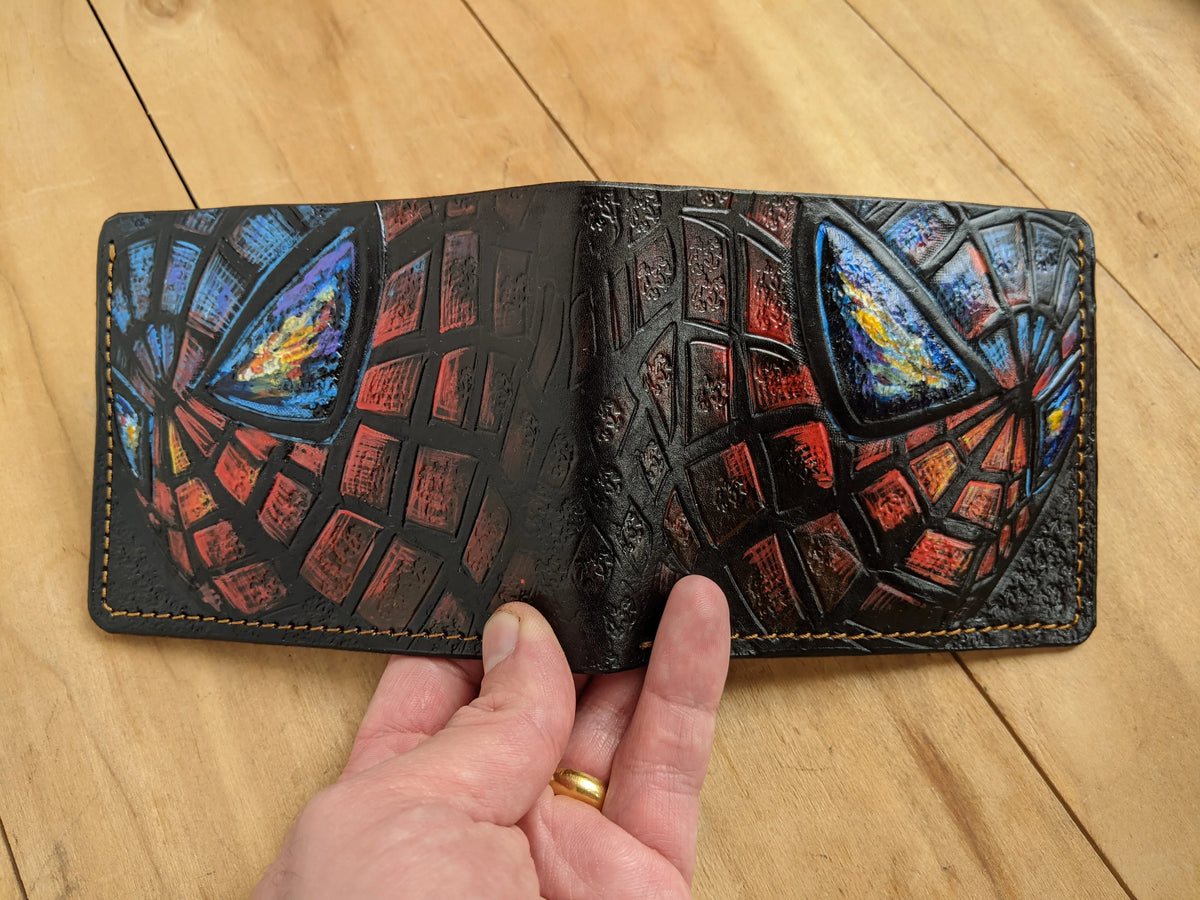 Open Spider-Man full-grain leather bifold wallet by Theodoros Leather held flat to display detailed hand-carved artwork.